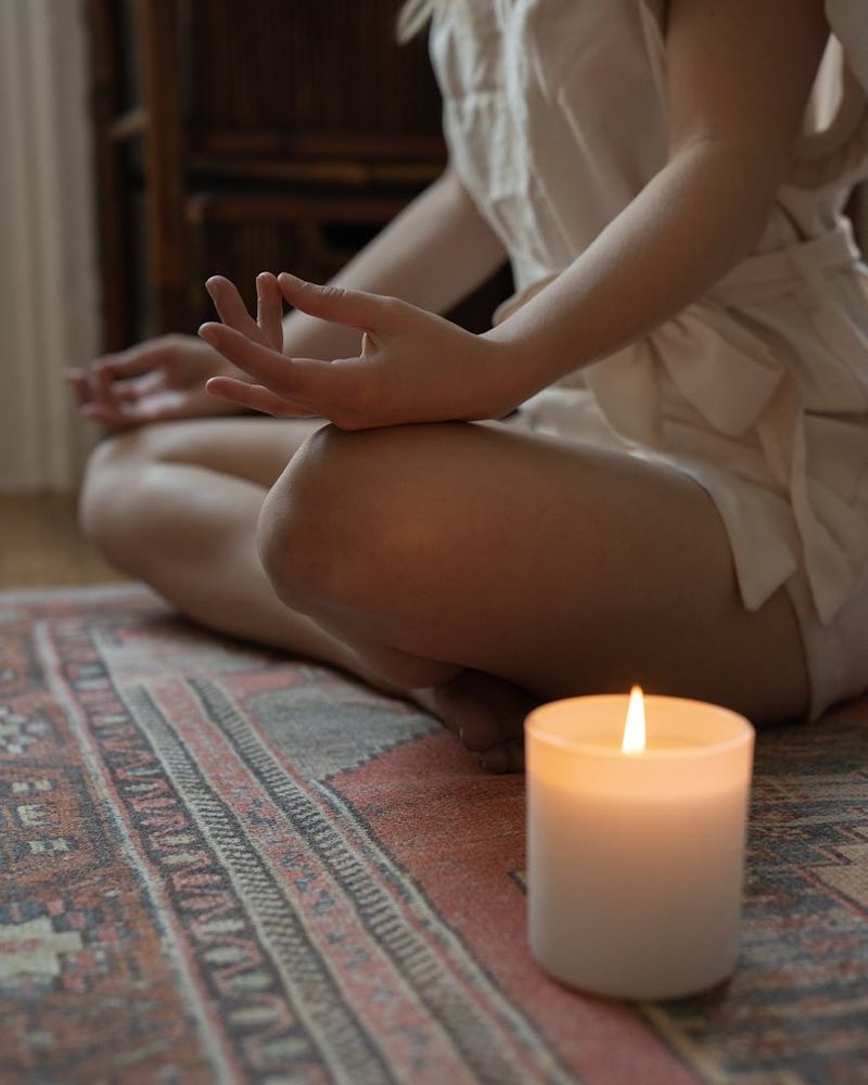 Woman in a calm yoga pose in a dark room with pink ambient light.